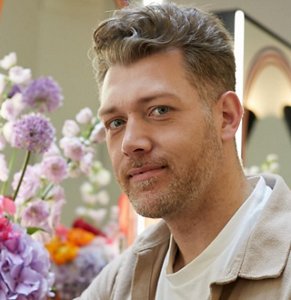 Hairdresser Michael Grey standing in front of a bouquet of flowers